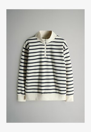 Prúžkovaný pulóver v krémovej a námorníckej farbe, s polozipsovým golierom, rebrovanými manžetami a mäkkou textúrou. Vertikálne prúžky vytvárajú jednotný vzor.