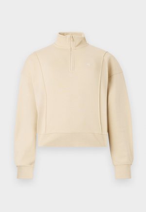 Sweatshirt cropped beige avec un col montant et un design zippé au quart. Présente des poignets côtelés et un logo subtil sur la poitrine. Texture douce.