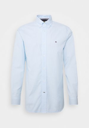 Camicia da uomo azzurro chiaro con sottili righe verticali, maniche lunghe e un piccolo logo sul lato sinistro del petto.