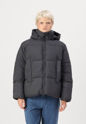 Giubbotto invernale nero con cappuccio, dotato di zip frontale, ampie tasche e una forma squadrata. Il materiale sembra liscio e imbottito.