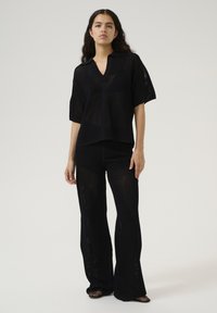 Set di top e pantaloni in maglia nera con vestibilità ampia, scollatura a V, maniche corte e motivo testurizzato con gambali larghi.