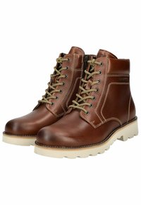 Botas de tobillo de cuero marrón con punta redonda, suela de goma beige y cordones dorados en contraste. Cremallera lateral para facilitar su uso. Detalles de costura visibles.