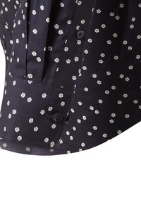 Navyblaue Hemdmanschette mit kleinem weißen Blumenmuster, schwarze knöpfbare Manschette und plissierter Stoffdetail nahe dem Ärmel.