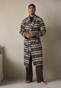 Kariertes Morgenmantel in Beige-, Marine- und Brauntönen mit Schalkragen, Gürtel und Taschen. Wird über dunklen Hosen getragen, mit lockerem Schnitt und glatter Textur.