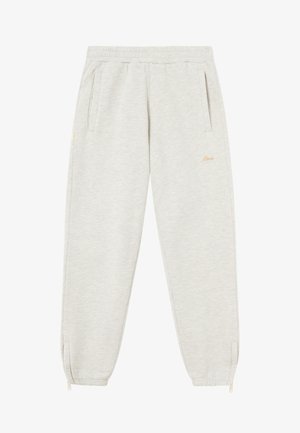 Hellgraue Jogginghosen mit weicher Textur, elastischem Bund, seitlichen Taschen und Reißverschlüssen an den Knöcheln. Dezente Markenstickerei in gold.
