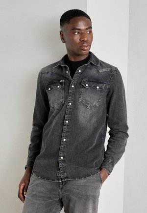 Dark grey denim shirt with button-up front, two chest pockets, and contrasting stitching. Long sleeves and a curved hem complete the design.