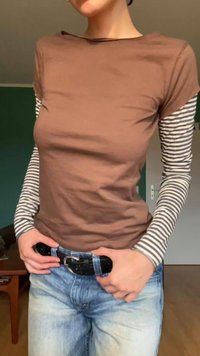 Brun kortermet topp lagd over en grå og hvit stripete langermet skjorte, sammen med blå jeans og et svart belte.