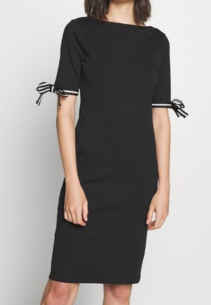 Black knee-length dress with elbow sleeves and black-and-white striped bows tied at each sleeve hem.