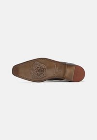 Sole di scarpa in pelle marrone con forma affusolata. Presenta dettagli in rilievo, bordi cuciti e una sezione del tallone in gomma di contrasto.