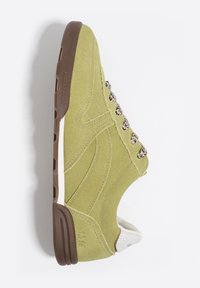 Zielony zamszowy sneaker o fakturowanym wykończeniu, z brązową gumową podeszwą i ozdobnymi sznurowadłami. Widok z boku podkreśla jego aerodynamiczny kształt.