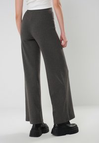 Mörkgrå revärerade vida byxor med hög midja och textilmaterial, kombinerat med kraftiga svarta plattformstövlar.