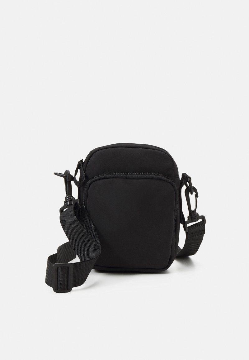 Borsa a tracolla nera in tessuto morbido, con scomparto principale con zip, tracolla regolabile e design minimalista.