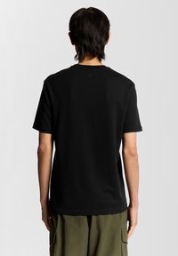 Sort kortærmet t-shirt med rund hals og glat tekstur, vist fra ryggen. Minimalistisk design uden synlige mønstre.