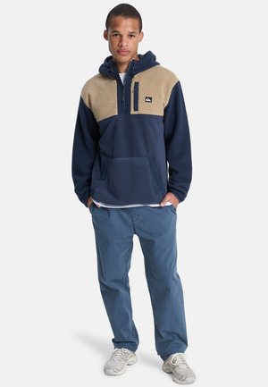 Navy and beige color-blocked hoodie made of fleece and soft fabric, featuring a zippered neck, front pocket, and elastic cuffs.