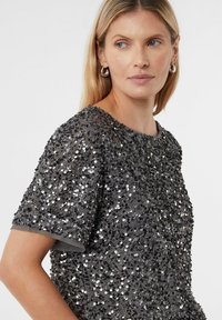 Graues Kurzarm-Oberteil, bedeckt mit schimmernden schwarzen Pailletten, mit rundem Ausschnitt und weichem Stoff darunter. Verfügt über ein schlichtes, klassisches Design.