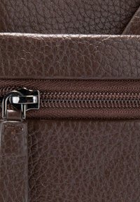 Borsa in pelle marrone con superficie testurizzata, cerniera argentata e dettagli in tessuto. Chiusura a cerniera sulla parte superiore per una conservazione sicura.