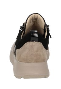 Schwarze und beige Sneaker mit einem Obermaterial aus Wildleder, glatten schwarzen Akzenten, einer Zuglasche hinten und einer strukturierten Gummisohle. Sichtbare Nähte und Futterdetails.
