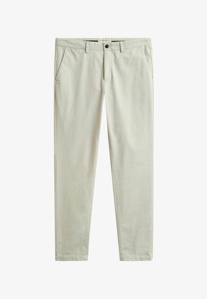 Beige slim-fit chino's met voorste knoop- en ritssluiting, zijzakken en riemlussen, plat gelegd op een witte achtergrond.