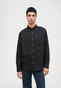 Fekete és lila kockás, hosszú ujjú ing gombolhat�ó gallérral, elülső zsebbel és ezüst gombokkal; sötétkék textúrált nadrággal viselve.