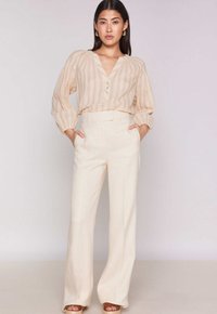 Blusa button-up leggera a righe in beige con scollatura a V e maniche ampie; abbinata a pantaloni a gamba larga crema a vita alta.