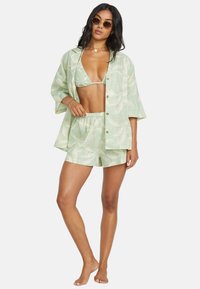 Set di due pezzi verde chiaro con fantasia composto da una camicia a maniche corte e pantaloni corti abbinati, realizzato in un tessuto morbido e leggero.