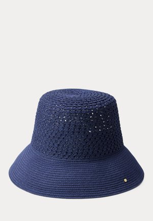 Granatowy kapelusz typu bucket z przewiewną plecioną koroną i szerokim, jednolitym rondem, ozdobiony małym, okrągłym złotym emblematem na rondzie.