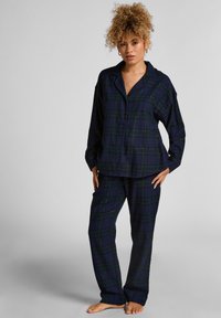 Marineblauw en groen geruite flanellen pyjama set met een knoopsluiting shirt en bijpassende broek; losse pasvorm met een zachte textuur.