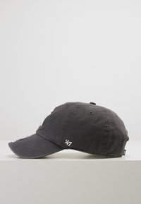 Gorra gris con visera curva, hecha de algodón. Presenta bordados blancos en la parte delantera y lateral, con orificios de ventilación en la corona.