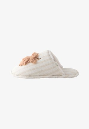 Beiger gestreifter Schlupfschuh mit weicher brauner Pompon-Dekoration und weißem flauschigem Innenfutter.