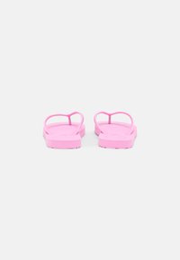 Chinelas rosa com alças em forma de coração, feitas de material de borracha macia, com sola plana e padrão de ranhura texturizado para melhor aderência.