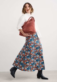 Rožinės odos peties rankinė su lygiu paviršiumi ir užtrauktuku. Suderinta su ilgais gėlėmis raštuotais sijonais mėlynos, oranžinės ir baltos spalvos.