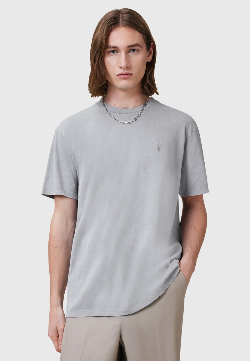 T-shirt grigio a maniche corte realizzato in tessuto morbido con una sottile texture, dotato di colletto rotondo e un piccolo logo sul petto.
