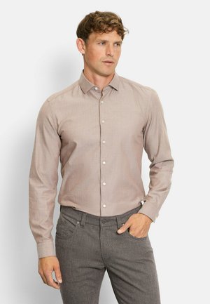 Light brown long-sleeve shirt with a button-down collar, featuring a subtle texture and white buttons, paired with dark patterned trousers.