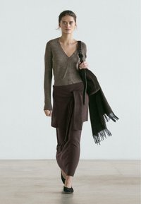 Brauner Strickcardigan mit Knopfdetail, kombiniert mit einem braunen Wickelrock. Akzentuiert mit einem dunklen Schal und einer schwarzen Tasche.