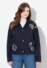 Marinblå cardigan med avslappnad passform, prydd med broderade frukter och blommor. Den har V-ringning och två framfickor med knapplås.