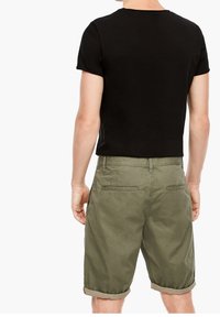 T-shirt noir ajusté et shorts verts olive. Les shorts ont un ourlet roulé, des poches arrière et un tissu texturé. Design simple et décontracté.