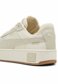 Sneaker in pelle bianca con accenti grigio chiaro, superficie texturizzata, punta rotonda, colletto imbottito e dettaglio con logo caratteristico sul tallone.