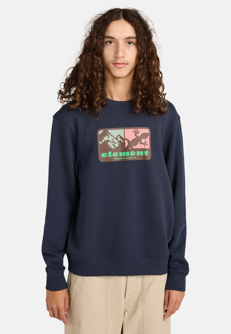 Granatowy sweatshirt o miękkiej teksturze, z prostokątną grafiką przedstawiającą góry i jaszczurkę, akcentowany zielonymi i różowymi kolorami.