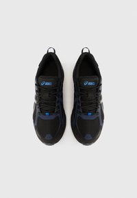 Čierne a námornícke tenisky s vrchnou časťou z oka, šnúrkami a modrým akcentom. Majú pevný podrážok a pútko na päte pre jednoduché obúvanie.