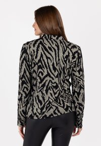 Maglione a righe zebra in grigio e nero, con una lavorazione a maglia testurizzata, maniche lunghe e colletto. La vista posteriore mostra una silhouette aderente.