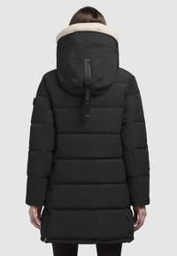 Schwarze gepolsterte Jacke mit großer Kapuze, ausgestattet mit einem beigen Fleece-Futter. Entworfen mit horizontalen Steppnähten und verstellbaren Riemen.