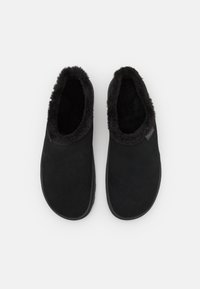 Czarne buty wsuwane z miękką, puszystą wyściółką. Wykonane z materiału przypominającego zamsz, z gładką powierzchnią i zaokrąglonym czubkiem.