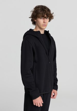 Felpa nera con zip realizzata in tessuto morbido, dotata di cappuccio, maniche lunghe e vestibilità affusolata. Texture liscia e dettagli di design minimal.