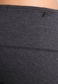 Leggings sportivi neri in tessuto testurizzato, con una vita elastica e una piccola tasca con zip sul retro.