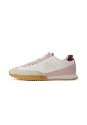 Sneaker bianco con dettagli in camoscio rosa, suola in gomma, punta arrotondata, chiusura con lacci e dettaglio logo testurizzato sul lato.