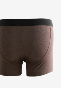 Rjave boxer hlače z črnim elastičnim pasom in gladko, raztegljivo teksturo. Oblikovane so s prilegajočem oblikovanjem in minimalnimi šivi.