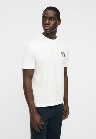 Λευκό βαμβακερό t-shirt με στρογγυλή λαιμόκοψη, με πολύχρωμο γραφικό σχέδιο στο αριστερό μέρος του στήθους. Κοντά μανίκια και κανονική εφαρμογή.