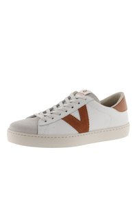 Baskets en cuir blanc avec un capuchon en daim gris clair et un logo V sur le côté en texture brune. Elles sont dotées de lacets beige et d'un design minimaliste.