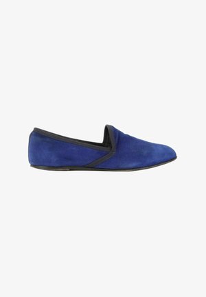 Chausson plat en daim bleu avec bordure noire et petit talon, vu de côté sur fond blanc.