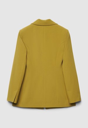 Blazer jaune moutarde avec une coupe ajustée, col cranté et épaules structurées, présentant une texture lisse et des lignes épurées.